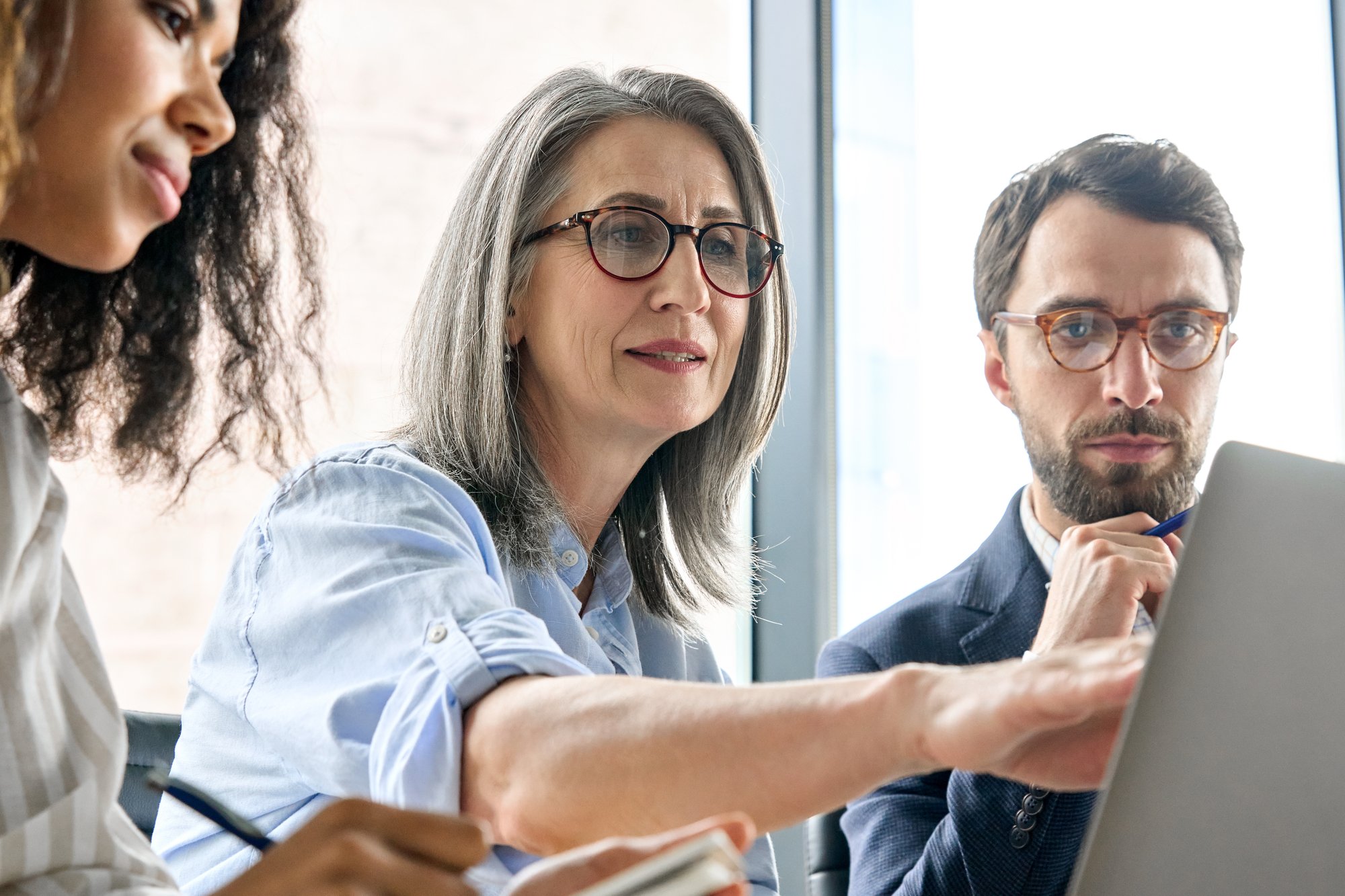 District - mature woman in group setting looking at computer 